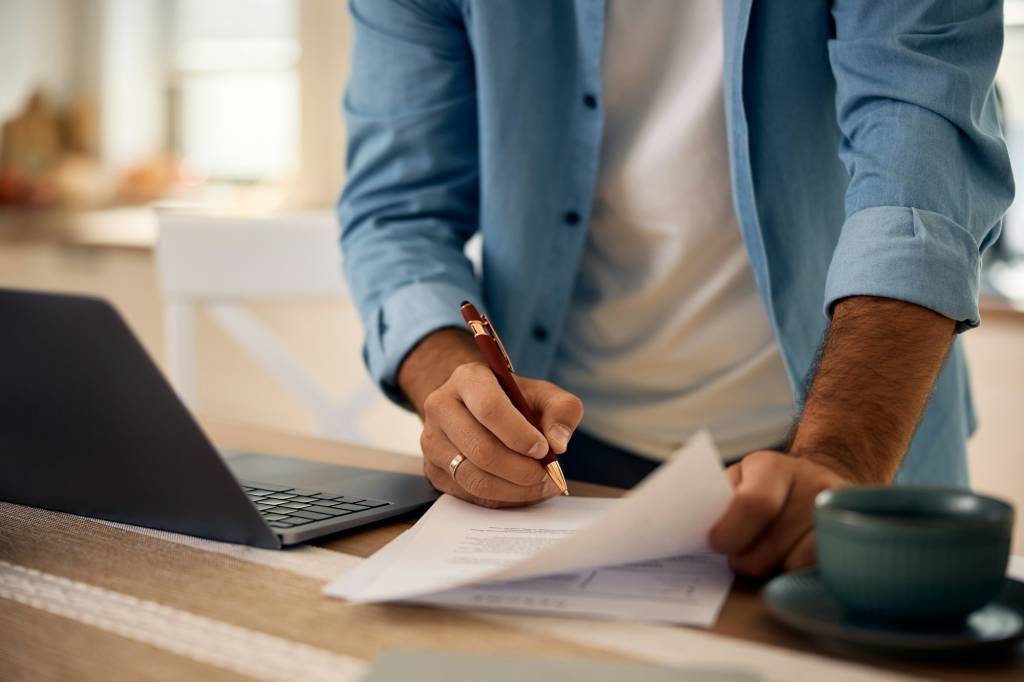 Close up of man signing documents while working at home.