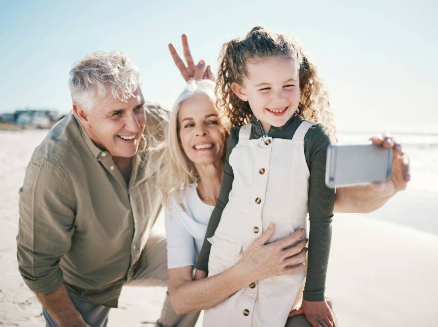 Family, selfie and beach holiday with peace sign, grandparents and young girl with a smile. Happy,
