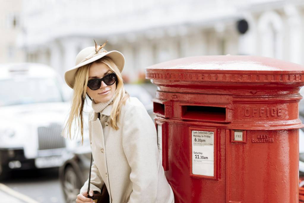 Stylish young woman waiting by red post box, London, England, UK