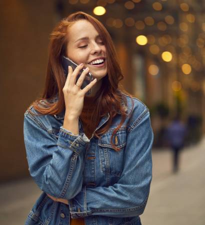 Female Vlogger Travelling Through City Making Phone Call On Mobile Phone On Street