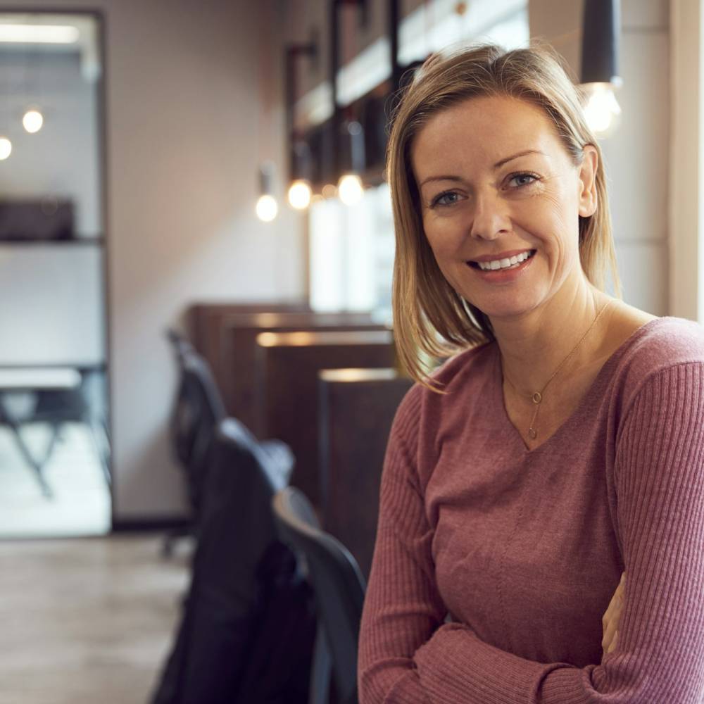 Head And Shoulders Portrait Of Smiling Mature Businesswoman Working In Modern Office